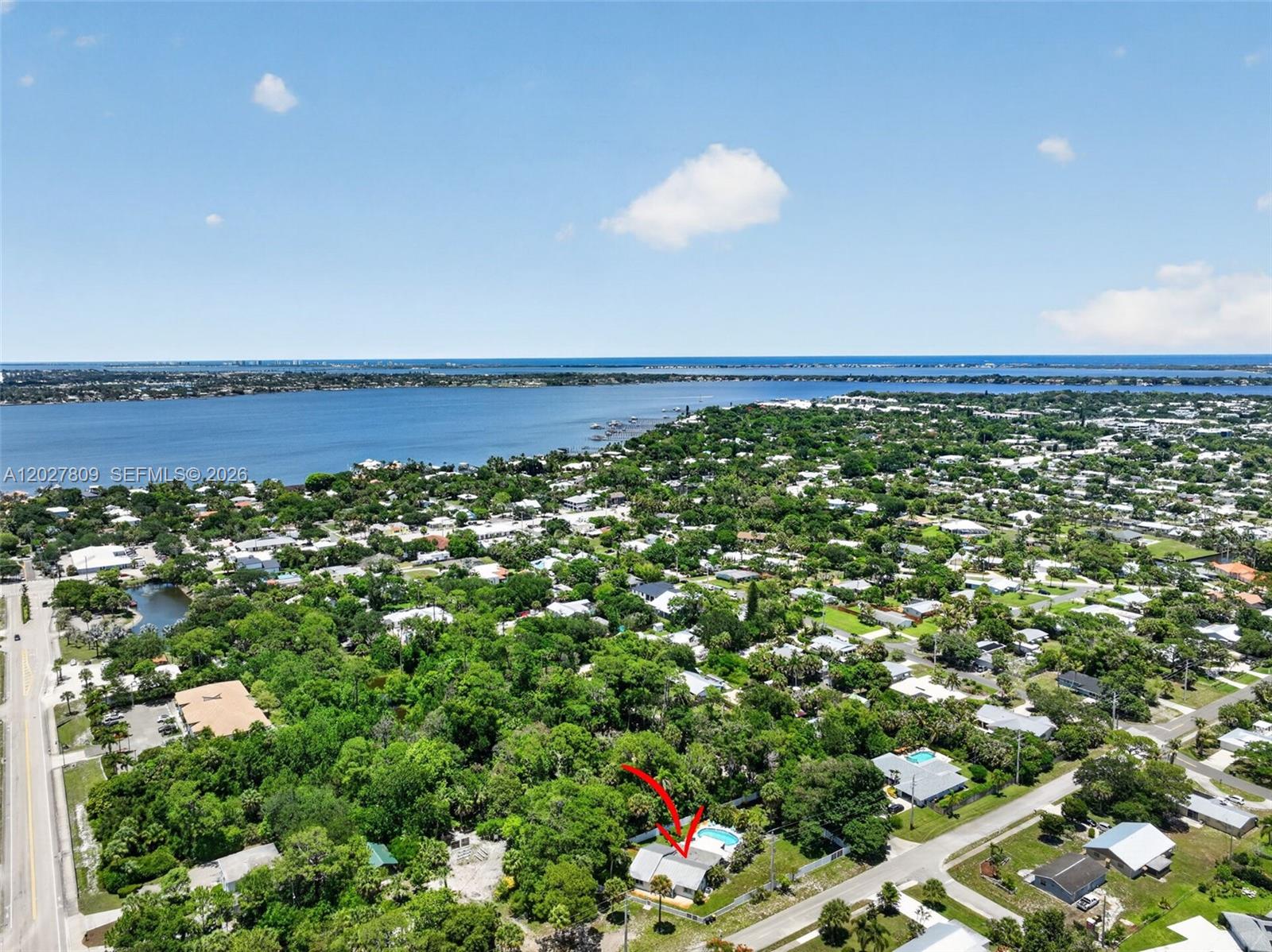 An aerial view shows a residential house with a pool surrounded by dense trees — 1023 SE 7th St, Stuart FL 34996, STUART, FL