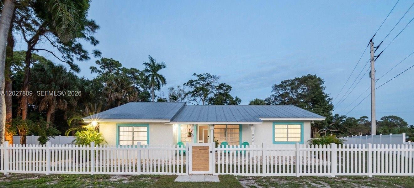 A single-story house with a metal roof and turquoise trim behind a white picket fence — 1023 SE 7th St, Stuart FL 34996, STUART, FL