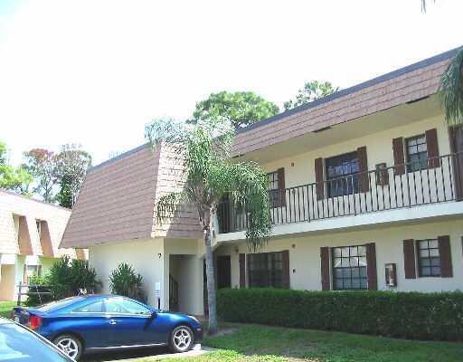 A two-story apartment building with a brown mansard roof and a blue car parked outside — 4101 Oak Terrace Drive, FL 33463, FL