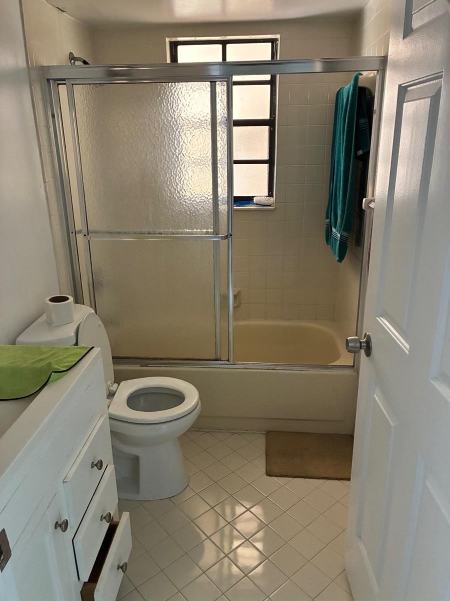 A bathroom with a white vanity, a toilet, and a shower-tub combination with sliding doors — 4101 Oak Terrace Drive, FL 33463, FL