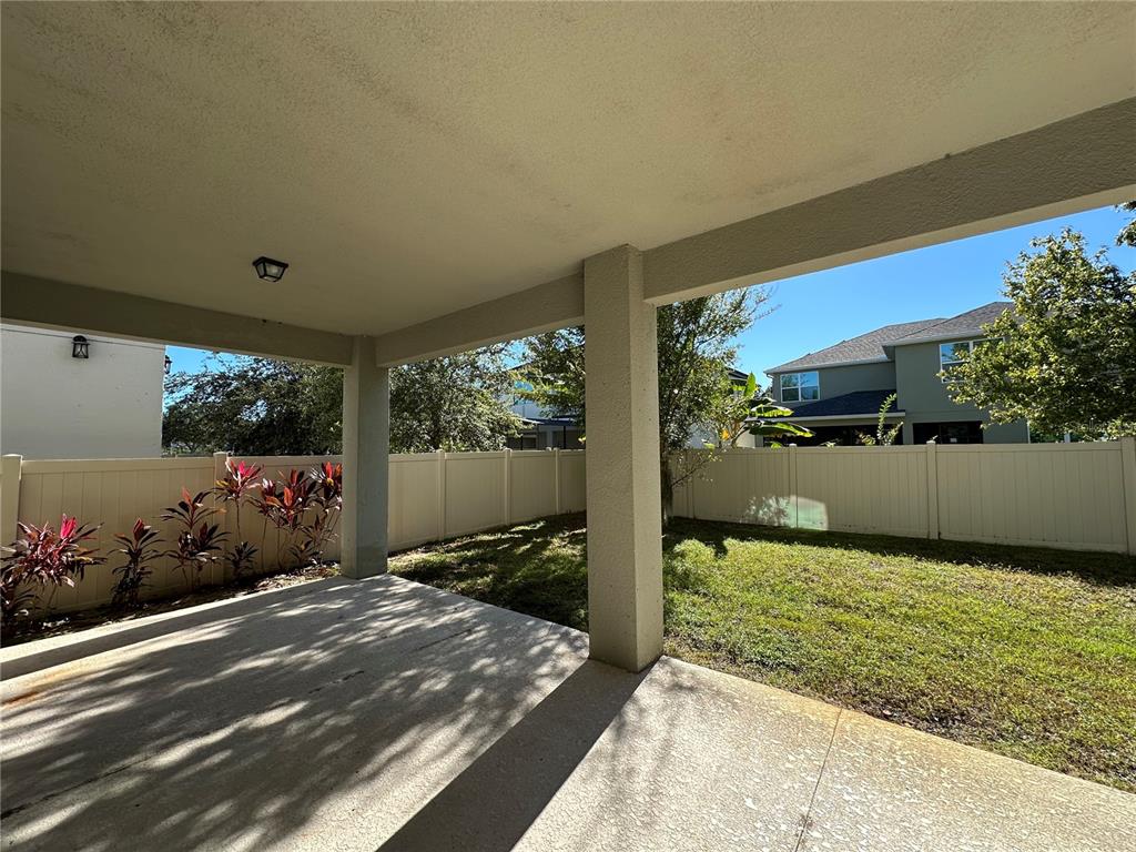 A covered concrete patio overlooks a fenced backyard with green grass and landscaping — 8712 CRESCENDO AVENUE, WINDERMERE, FL
