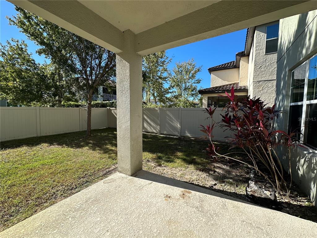 A concrete patio overlooks a grassy backyard enclosed by a white vinyl fence — 8712 CRESCENDO AVENUE, WINDERMERE, FL