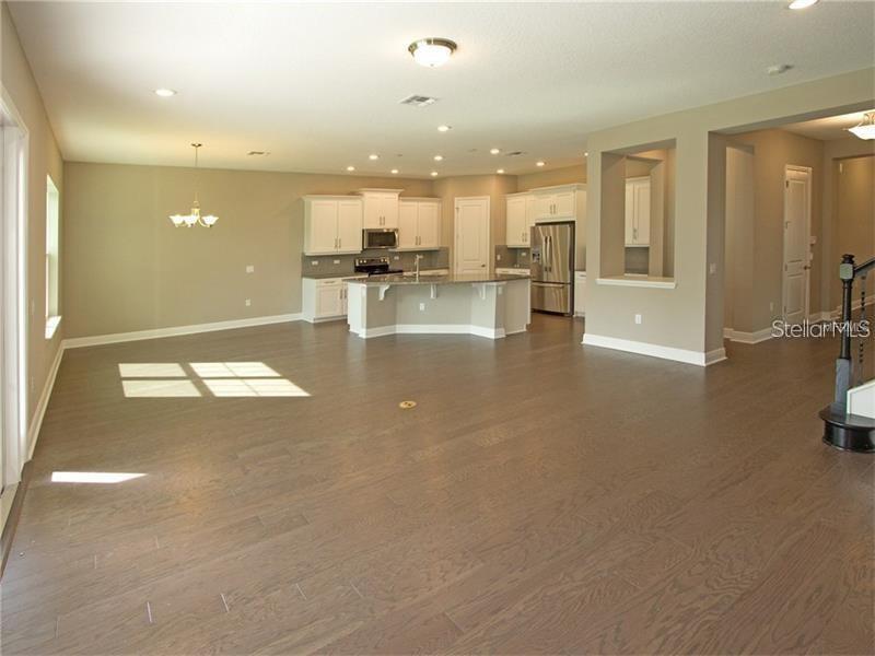 An open-concept kitchen with white cabinetry and a center island overlooks a large living area — 8712 CRESCENDO AVENUE, WINDERMERE, FL