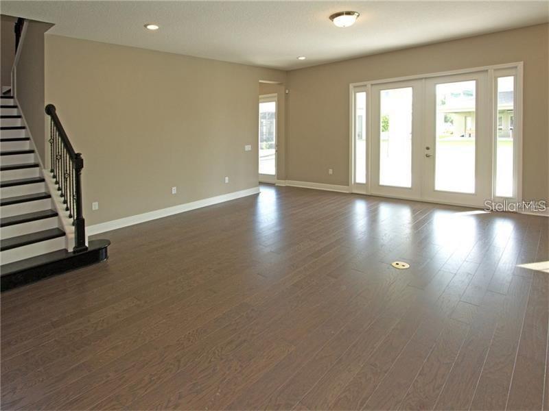 A living room features dark hardwood floors, a staircase with black railings, and glass patio doors — 8712 CRESCENDO AVENUE, WINDERMERE, FL