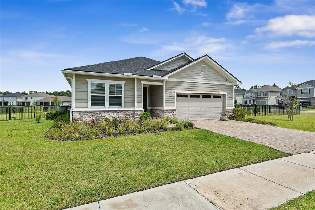 A single-story house with light green siding, a stone facade, and a two-car garage — 26 WINGED ELM, ST AUGUSTINE, FL