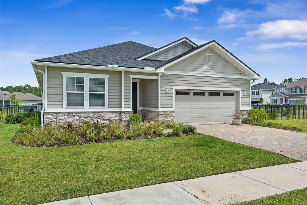 A single-story house with beige siding, a stone facade, and a paved driveway — 26 WINGED ELM, ST AUGUSTINE, FL