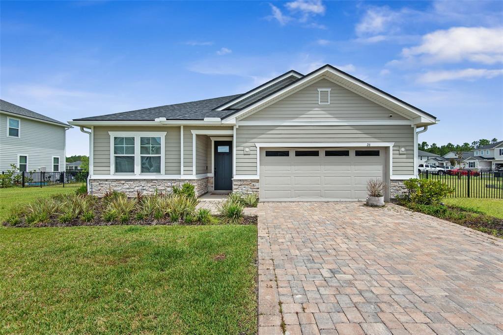 A single-story house with light green siding, a stone base, and a paved driveway — 26 WINGED ELM, ST AUGUSTINE, FL