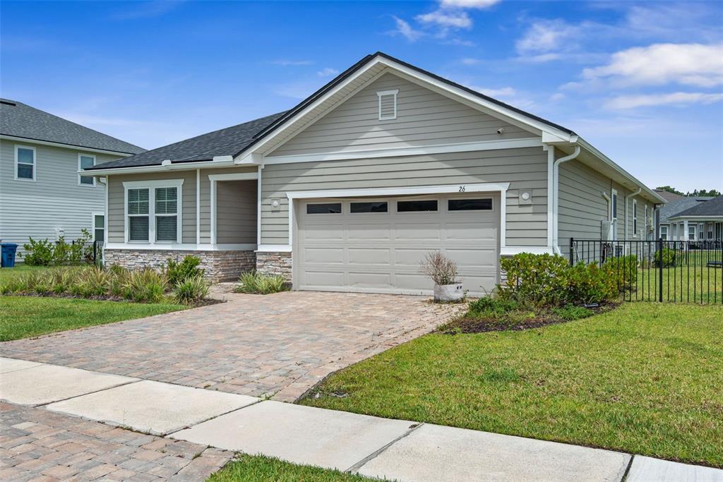 A one-story suburban house with light gray siding, a stone base, and a paved driveway — 26 WINGED ELM, ST AUGUSTINE, FL