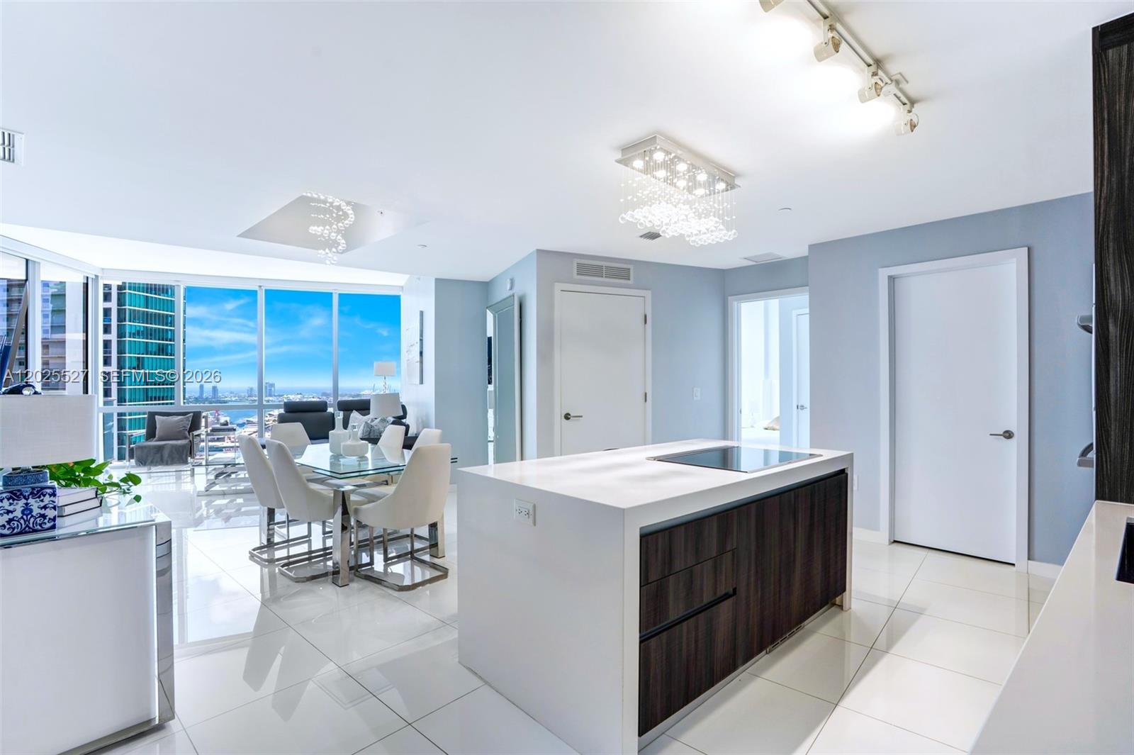 A modern kitchen with a white island and dark wood cabinets overlooks a dining area — 851 NE 1st Ave # 3909, Miami FL 33132, MIAMI, FL