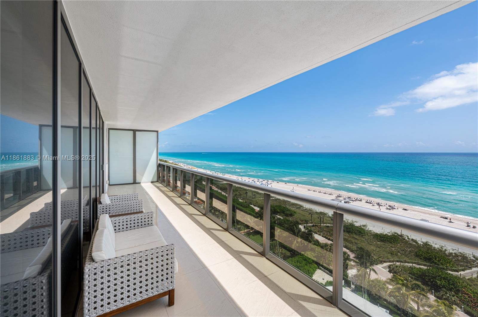 A balcony with outdoor seating overlooks a sandy beach and the ocean — 5875 Collins Ave # 1202, Miami Beach FL 33140, MIAMI BEACH, FL