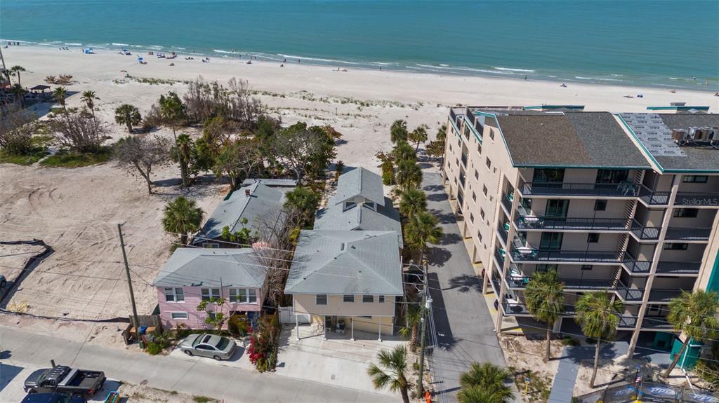 An aerial view shows two houses situated on a sandy beach next to a condominium — 13062 GULF BOULEVARD, MADEIRA BEACH, FL