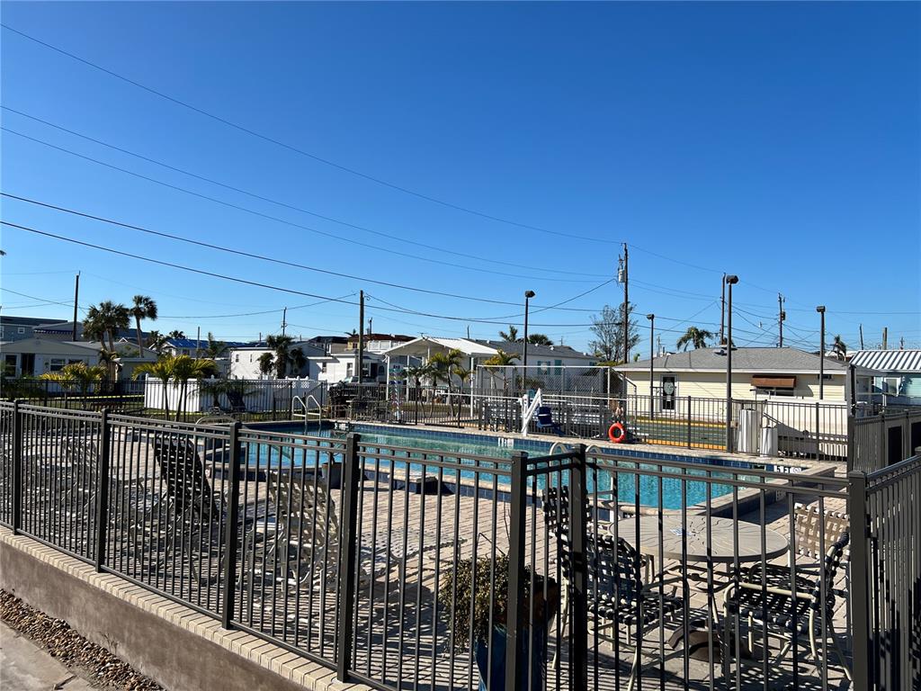 A fenced outdoor swimming pool area with patio furniture and surrounding residential buildings — 2601 GULF DRIVE N UNIT 502, BRADENTON BEACH, FL
