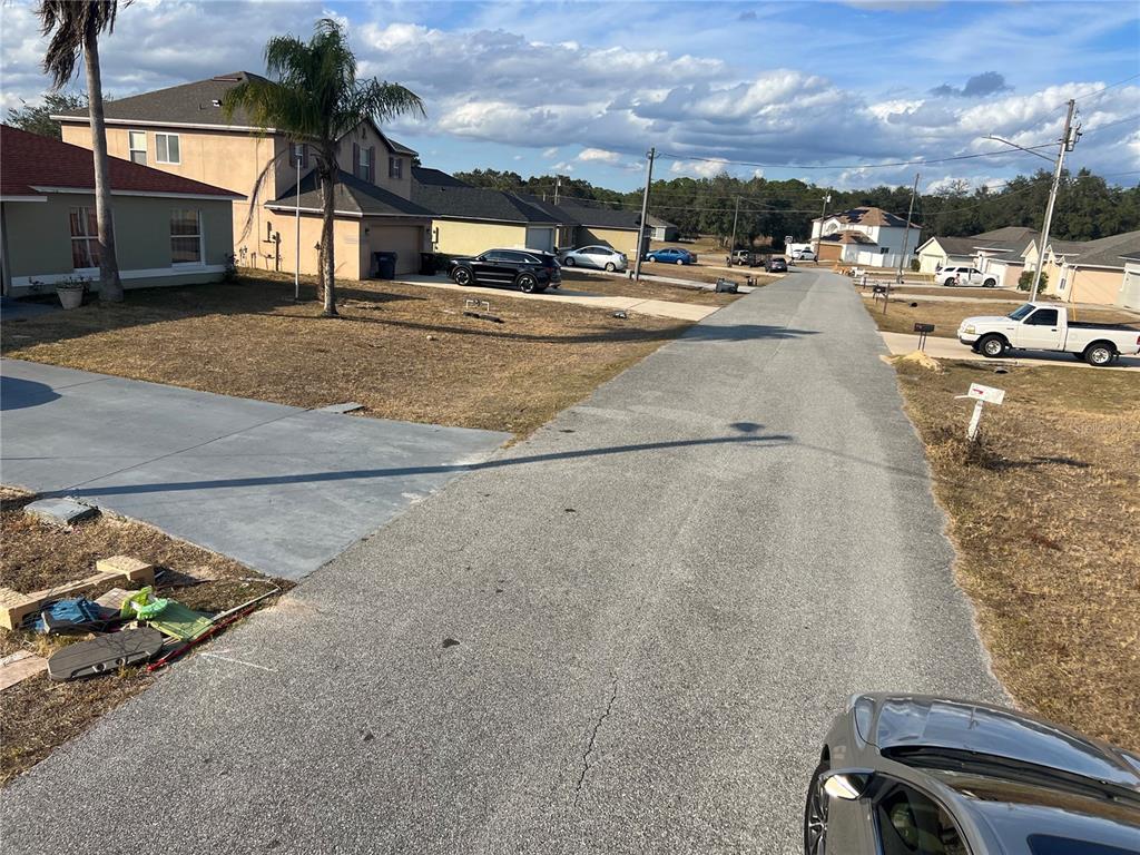 A residential street view showing houses, driveways, parked vehicles, and a clear blue sky — 1608 REDFIN DRIVE, KISSIMMEE, FL