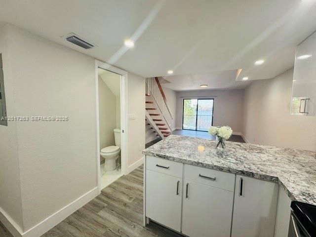 A kitchen with granite countertops overlooks a living area with stairs and a sliding door — 5650 W 26th Ct # 206, Hialeah FL 33016, HIALEAH, FL