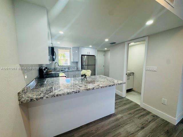 A kitchen features a granite countertop island, white cabinetry, and stainless steel appliances — 5650 W 26th Ct # 206, Hialeah FL 33016, HIALEAH, FL