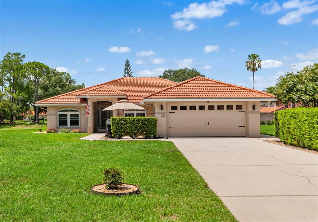 A single-story house with a tile roof, a two-car garage, and a green lawn — 120 MORNING GLORY CIRCLE, WINTER HAVEN, FL