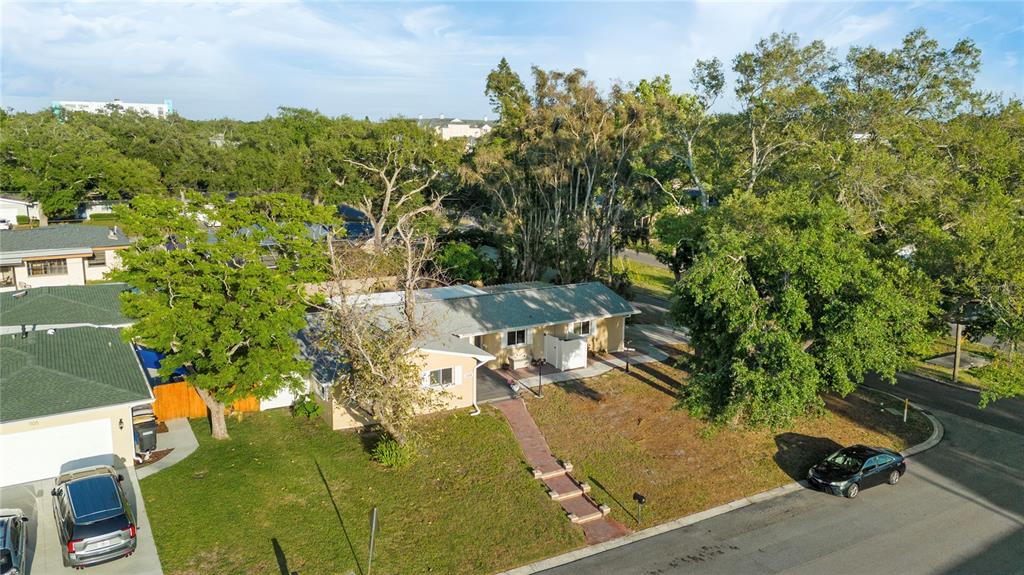 An aerial view shows a single-story house with a tan exterior and a paved walkway — 1109 S SAN REMO AVENUE, CLEARWATER, FL