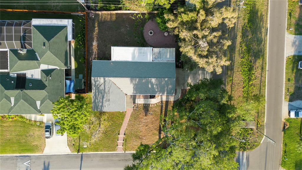 An aerial view shows a house with a green roof, a driveway, and a backyard — 1109 S SAN REMO AVENUE, CLEARWATER, FL