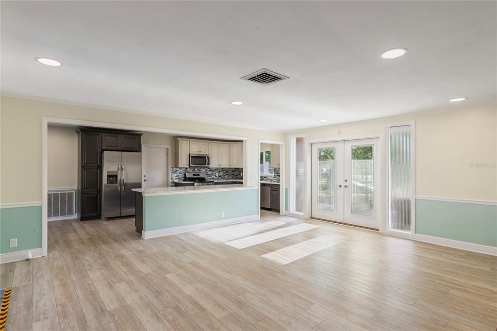 A bright, open-concept kitchen and dining area features light wood flooring and glass patio doors — 1109 S SAN REMO AVENUE, CLEARWATER, FL