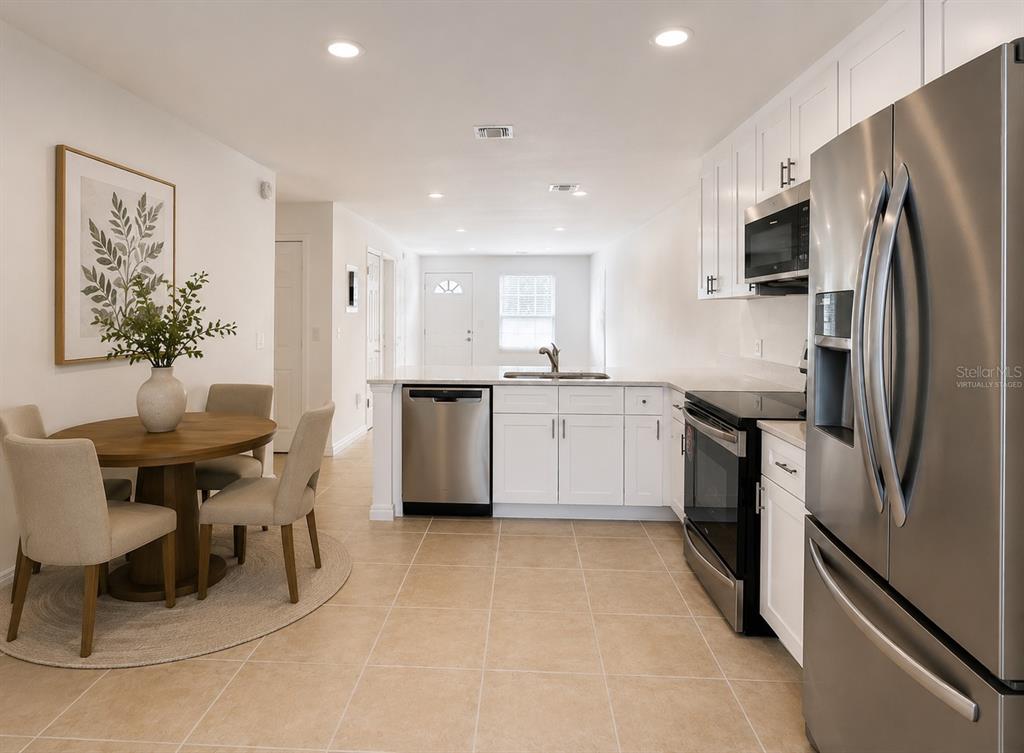 A kitchen with white cabinets, stainless steel appliances, and a dining area with a round table — 1255 SOPHIE BOULEVARD, ORLANDO, FL