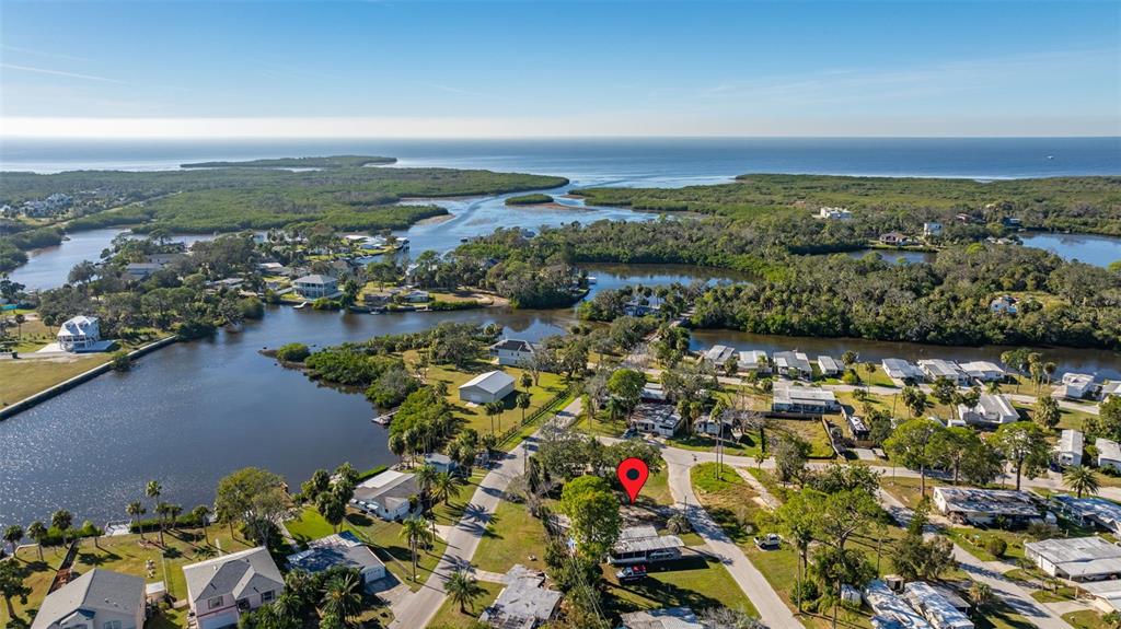 This aerial view shows a residential neighborhood with houses, trees, and waterways near the coast — 4836 SNUG HARBOR ROAD, NEW PORT RICHEY, FL