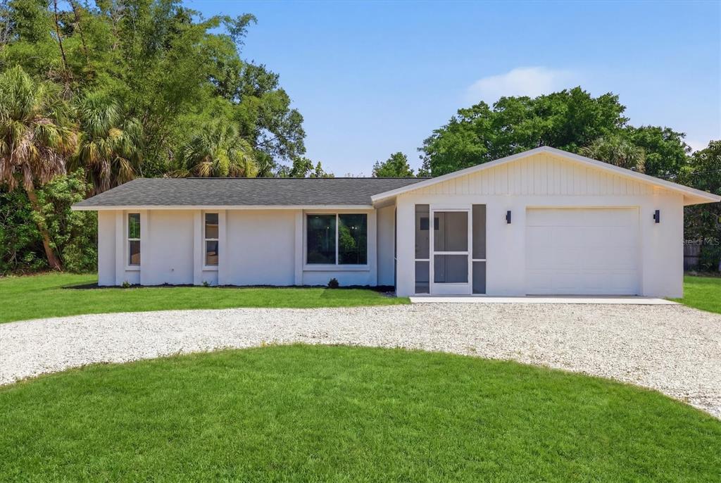 A single-story white house with a gravel driveway and a one-car garage — 432 OLIVIA ROAD, VENICE, FL