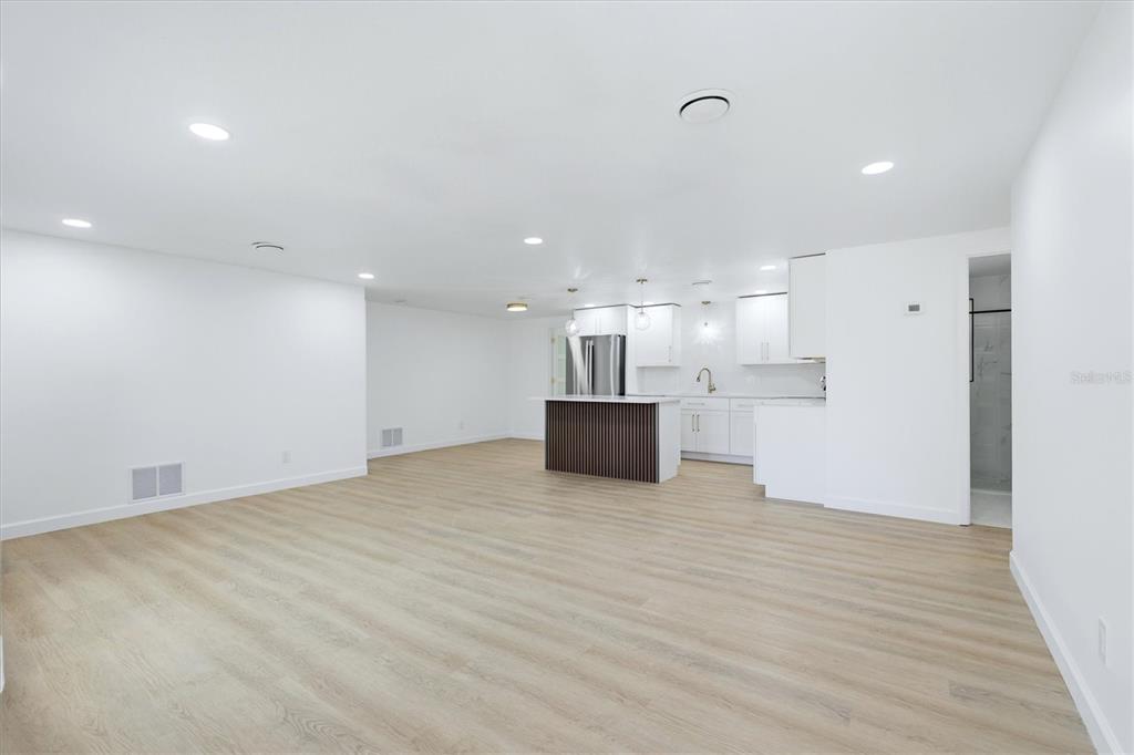 An open-concept living area features light wood-look flooring, white walls, and a modern kitchen island — 432 OLIVIA ROAD, VENICE, FL