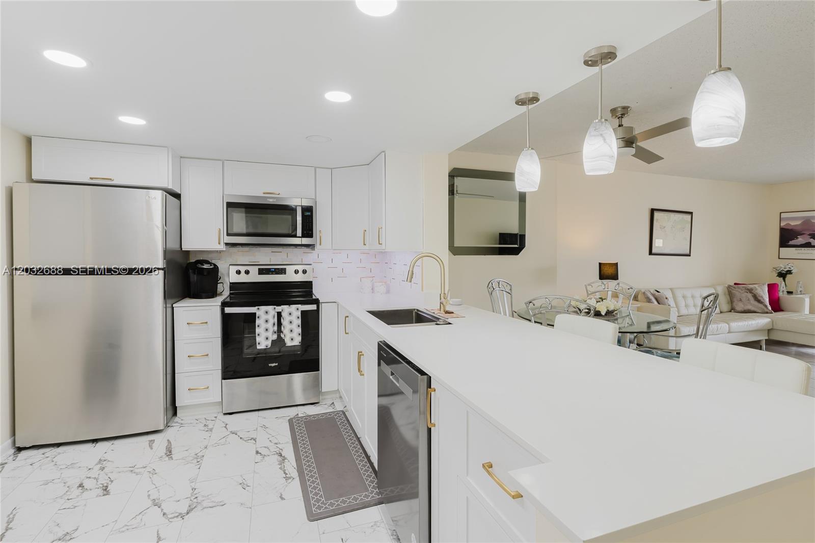 A modern kitchen features white cabinets, stainless steel appliances, and a white quartz countertop island — 424 SE 10th St # 204, Dania Beach FL 33004, DANIA BEACH, FL