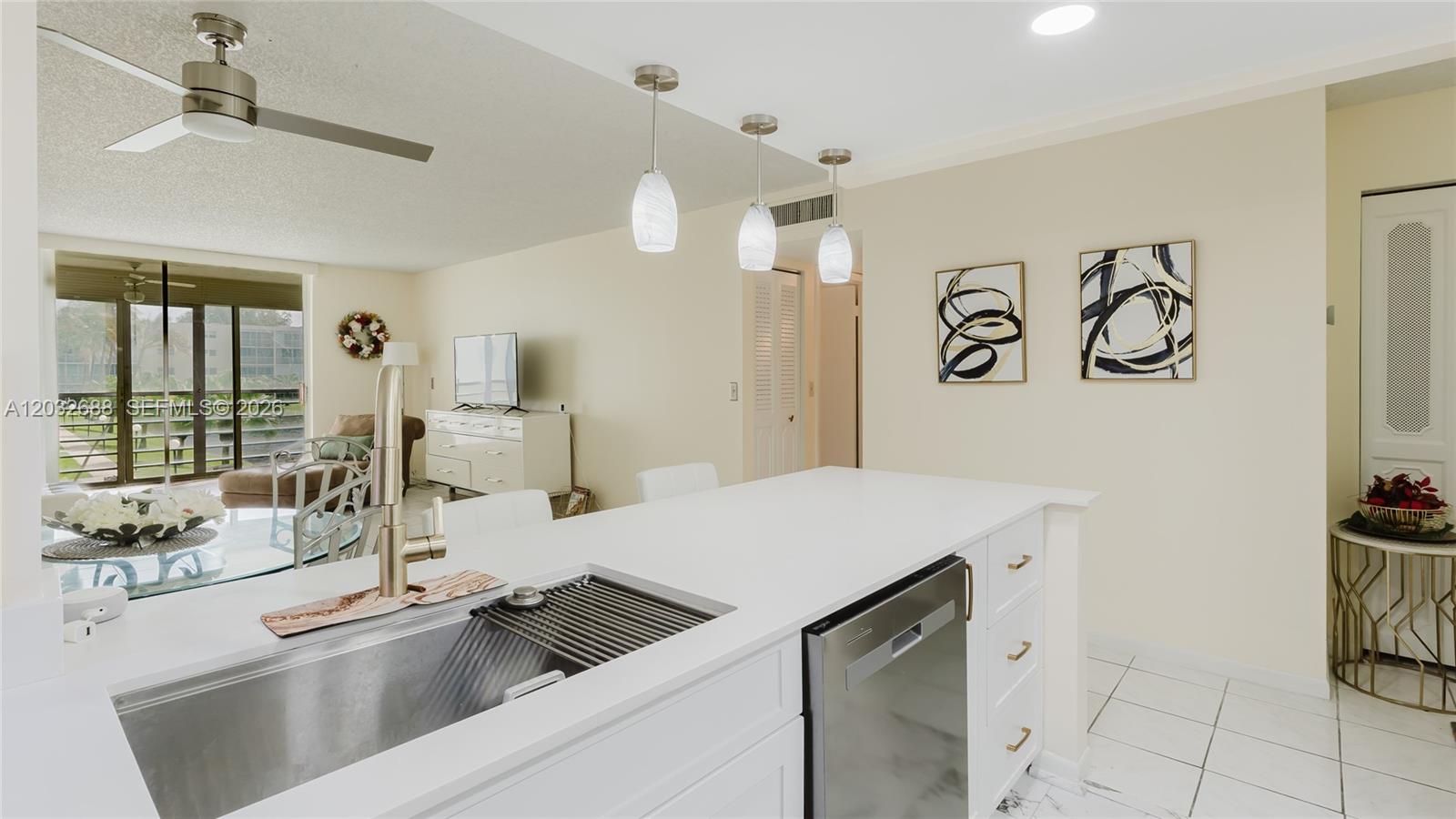 A modern kitchen island with a stainless steel sink overlooks a bright, open-concept living area — 424 SE 10th St # 204, Dania Beach FL 33004, DANIA BEACH, FL
