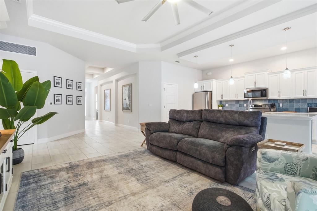 A living room with a grey sofa, area rug, and an open kitchen with white cabinets — 24 SPRING STREET, PALM COAST, FL