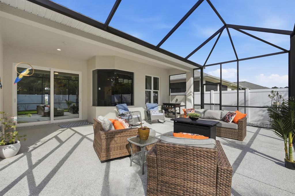 A screened-in patio features wicker furniture, a fire pit table, and a concrete floor — 24 SPRING STREET, PALM COAST, FL