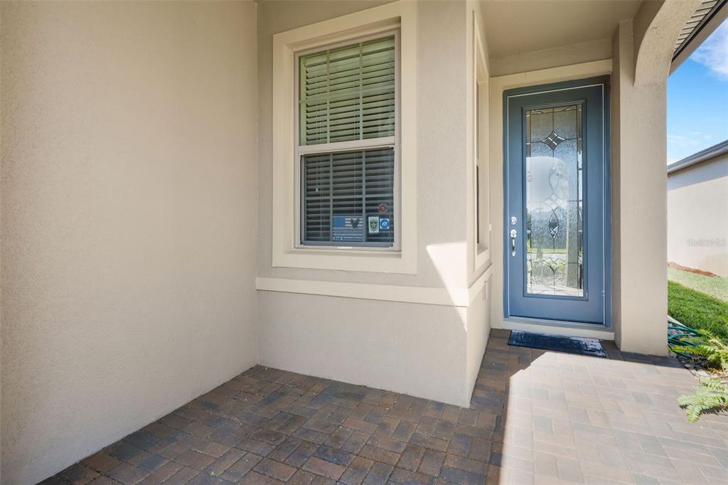 A paved entryway features a blue front door with a decorative glass insert and window — 1032 SALAMANCA PLACE, DAVENPORT, FL