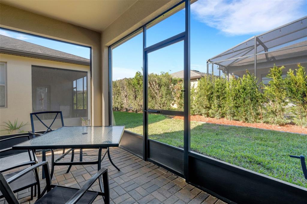 A screened-in patio with a glass-top table, brick pavers, and a view of the yard — 1032 SALAMANCA PLACE, DAVENPORT, FL