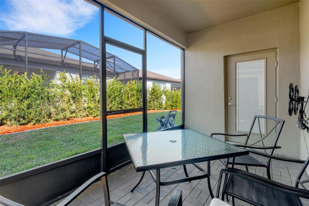 A screened-in patio features a glass-top table, chairs, and a view of a grassy backyard — 1032 SALAMANCA PLACE, DAVENPORT, FL