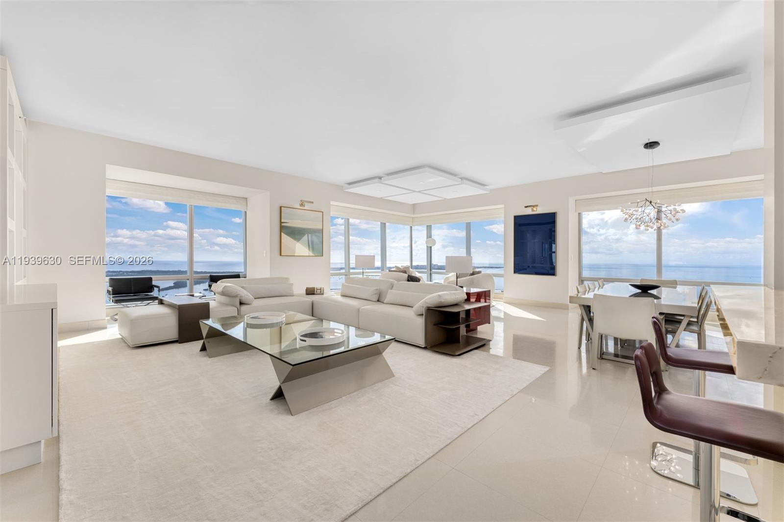 A modern, open-concept living and dining area features floor-to-ceiling windows with expansive ocean views — 1425 Brickell Ave # 56F, Miami FL 33131, MIAMI, FL