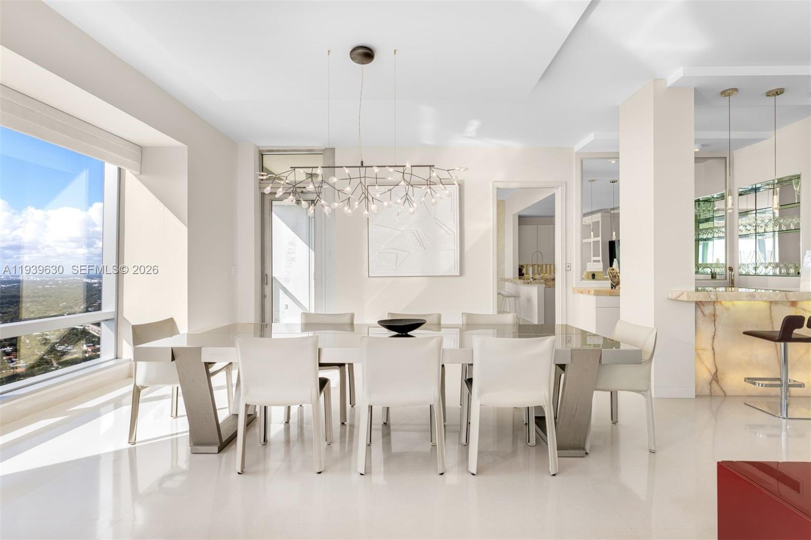 A modern dining room features a large white table, eight chairs, and a branch-style chandelier — 1425 Brickell Ave # 56F, Miami FL 33131, MIAMI, FL