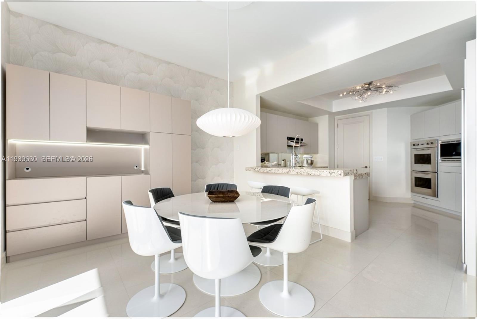 A modern dining area features a round table with white chairs and built-in cabinetry — 1425 Brickell Ave # 56F, Miami FL 33131, MIAMI, FL