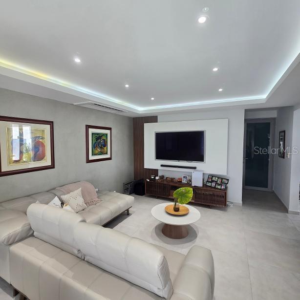 A living room features a light-colored sectional sofa, a wall-mounted television, and recessed lighting — 1 RUBI, VEGA ALTA, PR