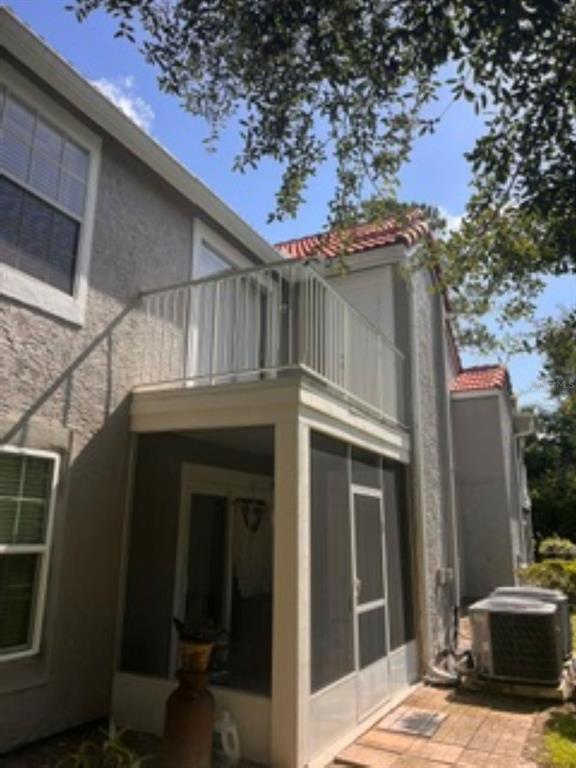 A two-story building exterior features a screened-in ground floor patio and an upper-level balcony — 1149 EXCELLER COURT UNIT 201, CASSELBERRY, FL