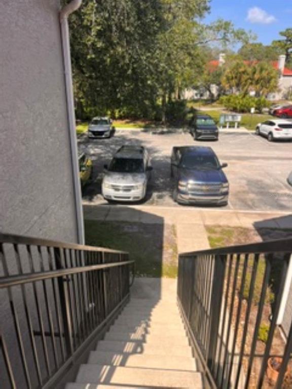An outdoor staircase leads down to a parking lot with several parked cars and trees — 1149 EXCELLER COURT UNIT 201, CASSELBERRY, FL