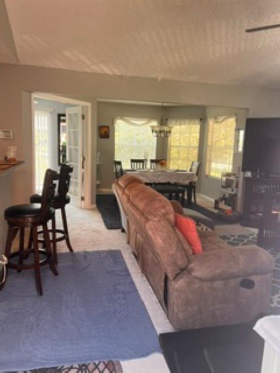 A living room with a brown reclining sofa, bar stools, and a dining area beyond — 1149 EXCELLER COURT UNIT 201, CASSELBERRY, FL