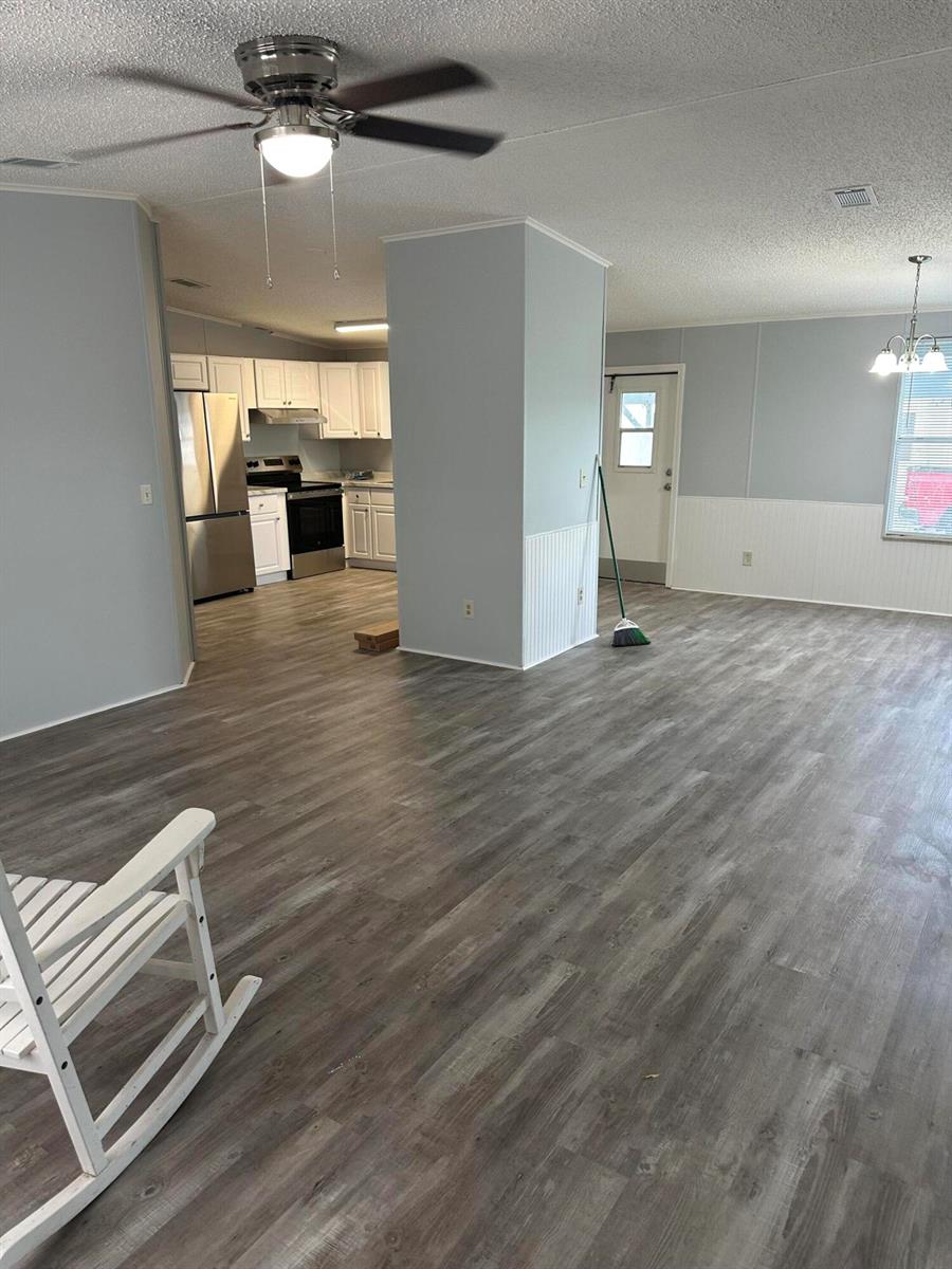 An open-concept living area features light gray walls, wood-look flooring, and a kitchen with white cabinets — 528 Tropical Isles Circle, Fort Pierce FL 34982, FORT PIERCE, FL