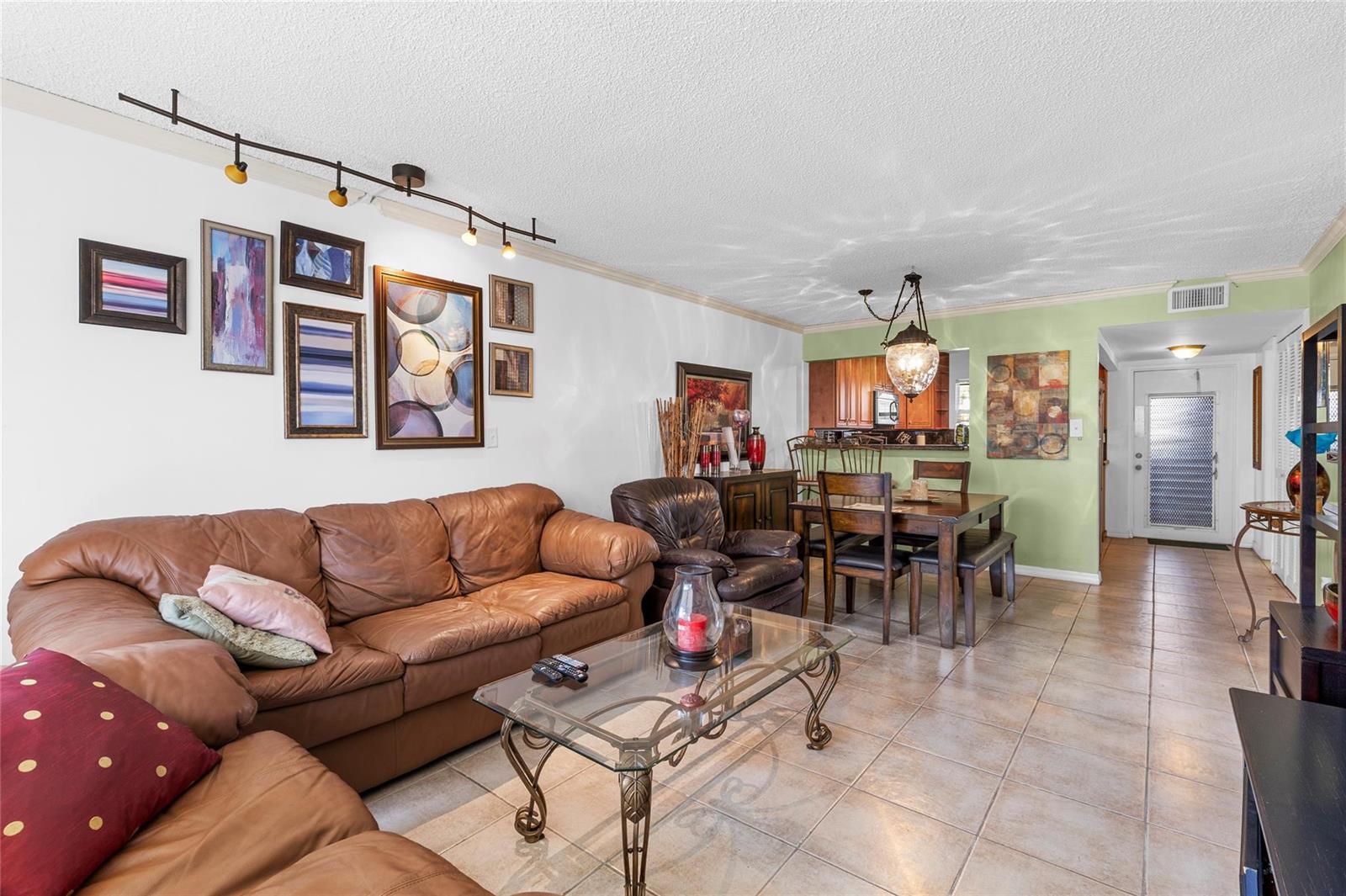 A living room with a brown leather sofa, glass coffee table, and adjacent dining area — 9350 Sunrise Lakes Boulevard # 101, Sunrise FL 33322, SUNRISE, FL