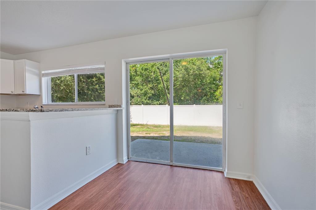 An interior view of a dining area with wood-look flooring, a sliding glass door, and kitchen — 10225 SUMMERVIEW CIRCLE, RIVERVIEW, FL