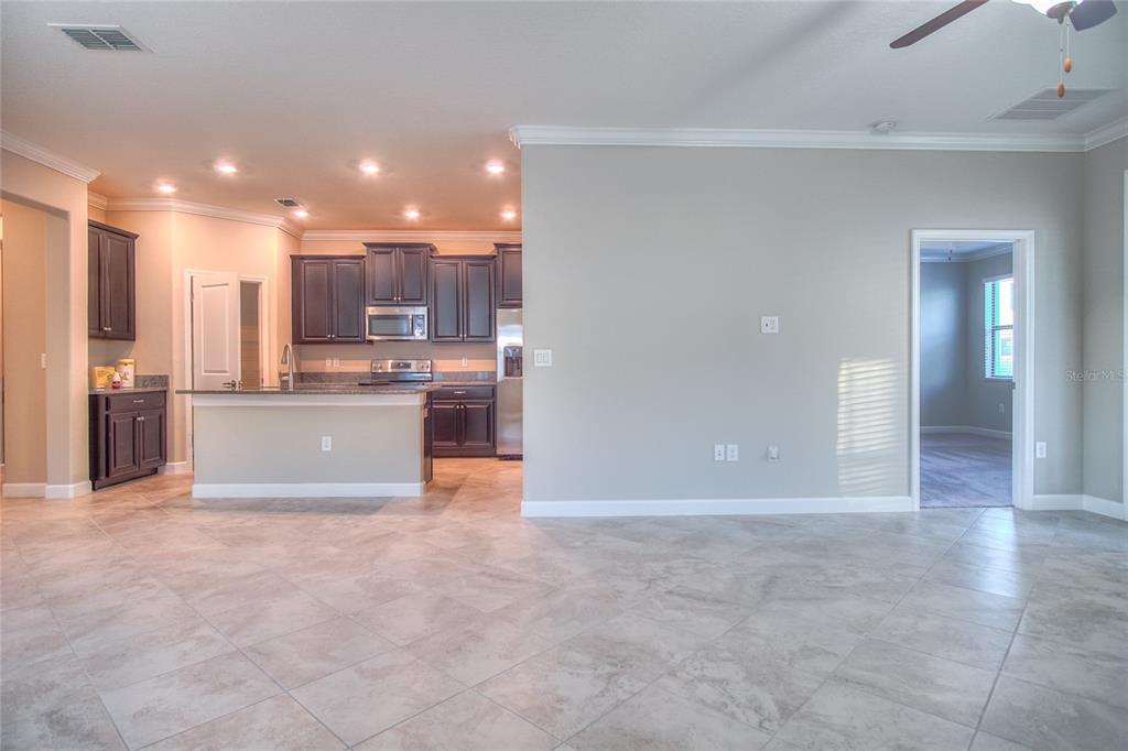 An open-concept kitchen with dark cabinets and granite countertops overlooks a tiled living area — 1212 MONTGOMERY BELL ROAD, WESLEY CHAPEL, FL