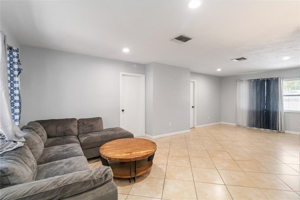 A living room features light gray walls, beige tile flooring, a gray sectional, and a coffee table — 1624 BLOOMFIELD AVENUE, DELTONA, FL