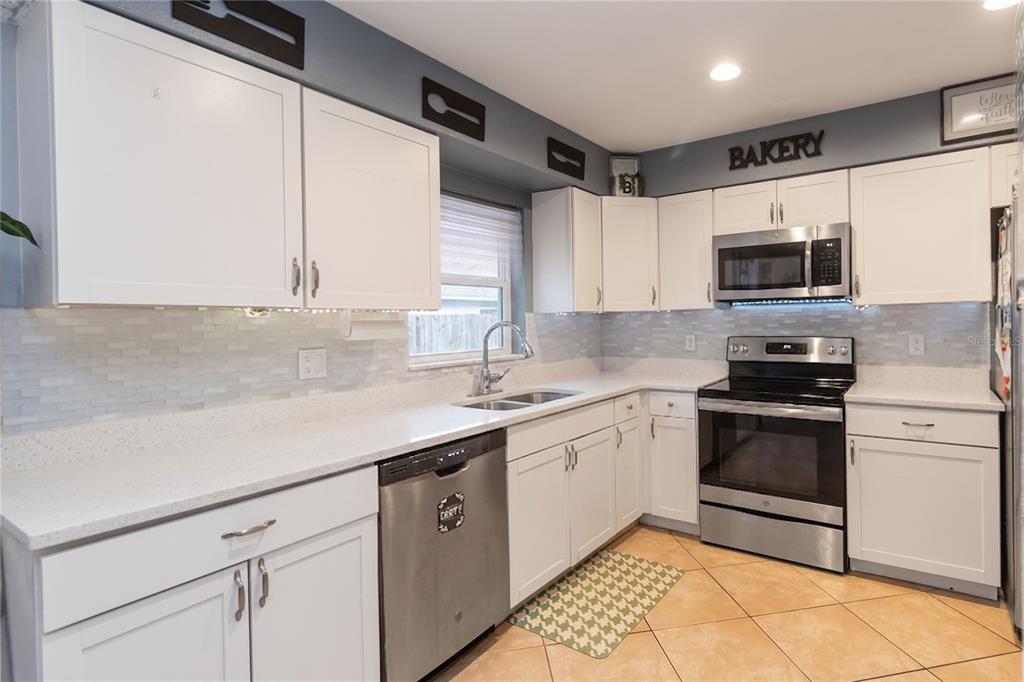 A kitchen with white cabinets, stainless steel appliances, light countertops, and a tiled backsplash — 1624 BLOOMFIELD AVENUE, DELTONA, FL