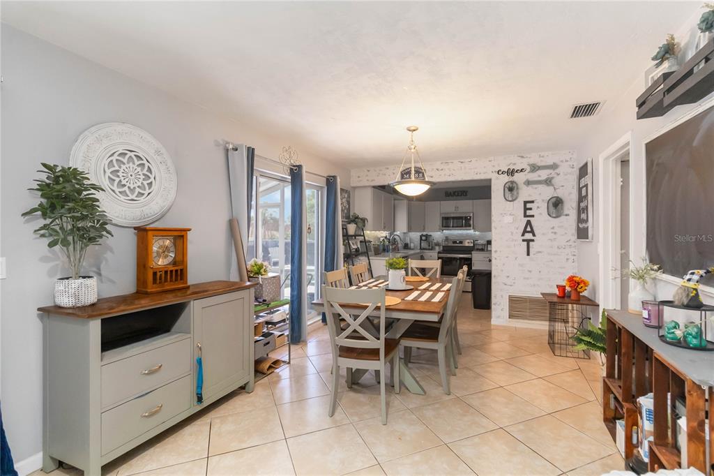 A dining area with tile floors, a wooden table, and a view into the kitchen — 1624 BLOOMFIELD AVENUE, DELTONA, FL