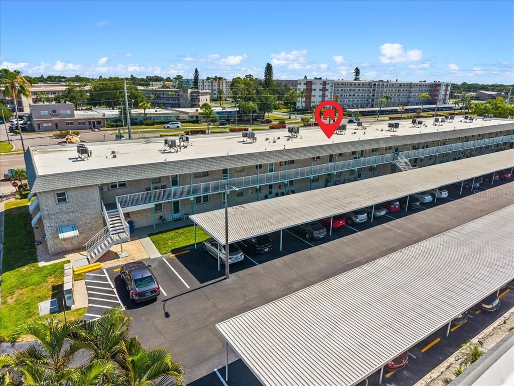 An aerial view shows a multi-story apartment building with a covered parking lot — 5357 81ST STREET N UNIT 18, ST PETERSBURG, FL