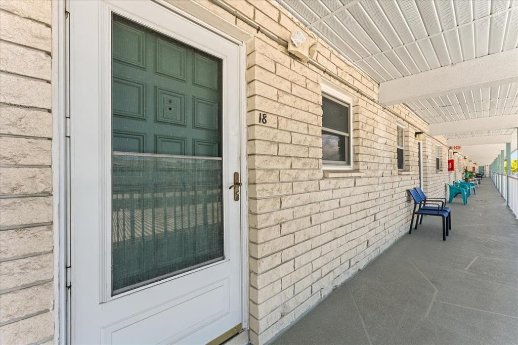 A white door with a screen and the number 18 sits on a brick walkway — 5357 81ST STREET N UNIT 18, ST PETERSBURG, FL